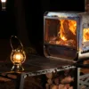 Table Master Ultra wood stove glowing at night beside a lantern and tent